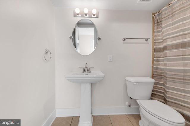 bathroom featuring toilet, tile patterned floors, and a shower with curtain