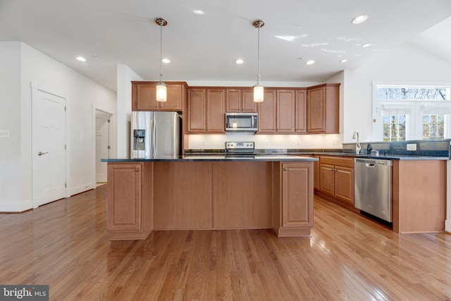 kitchen featuring a center island, stainless steel appliances, light hardwood / wood-style flooring, and hanging light fixtures