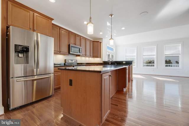 kitchen with stainless steel appliances, sink, a center island, pendant lighting, and light hardwood / wood-style floors