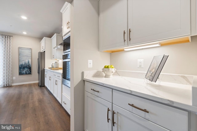 kitchen with light stone countertops, dark hardwood / wood-style floors, appliances with stainless steel finishes, and white cabinetry