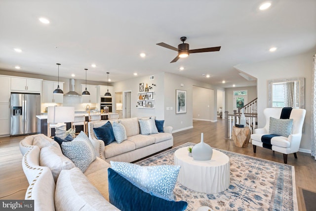 living room featuring ceiling fan, sink, and light hardwood / wood-style floors