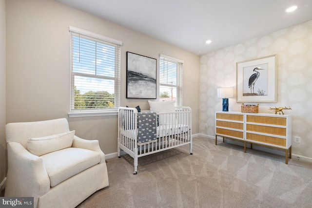 bedroom featuring light carpet, multiple windows, and a crib