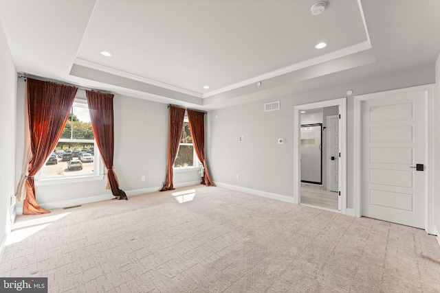 unfurnished bedroom featuring light carpet and a tray ceiling