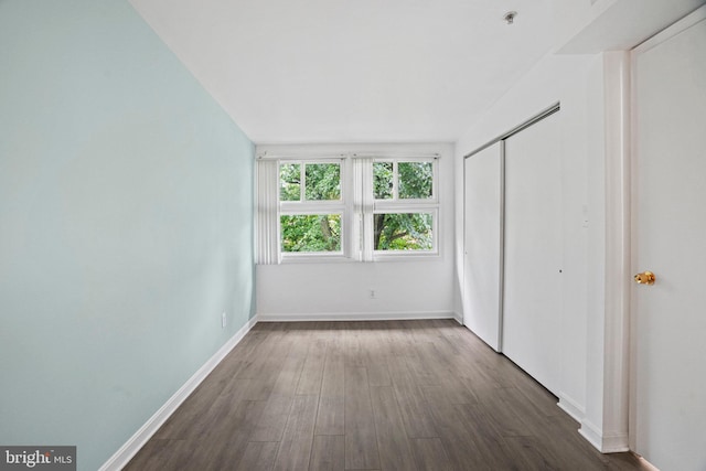 unfurnished bedroom featuring dark hardwood / wood-style flooring and a closet