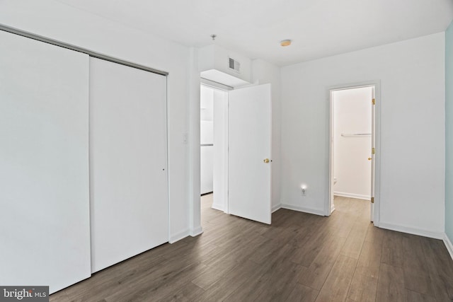 unfurnished bedroom featuring a closet and dark wood-type flooring