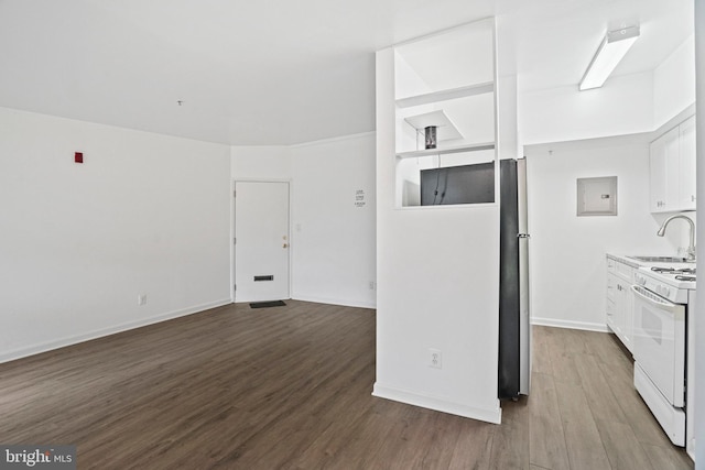 kitchen with white gas range, sink, stainless steel fridge, hardwood / wood-style floors, and white cabinets