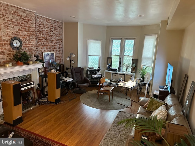 living room with light hardwood / wood-style floors and brick wall