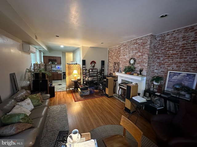 living room with light hardwood / wood-style floors, a wall mounted air conditioner, and brick wall