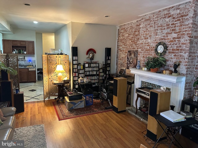 living room with light hardwood / wood-style floors and brick wall