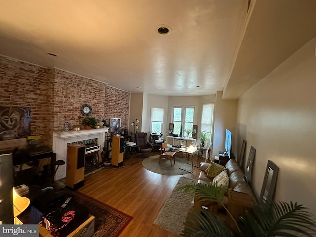 living room with light hardwood / wood-style flooring, brick wall, and a fireplace