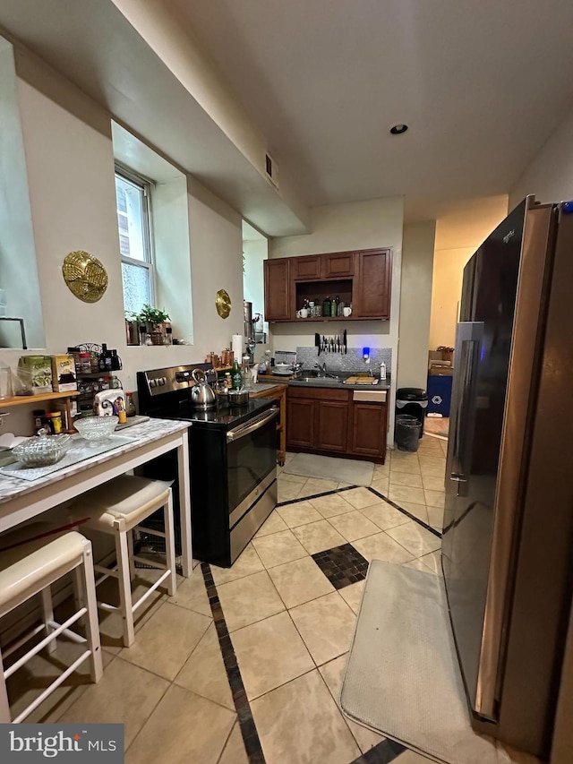 kitchen featuring light tile patterned flooring, stainless steel appliances, and sink