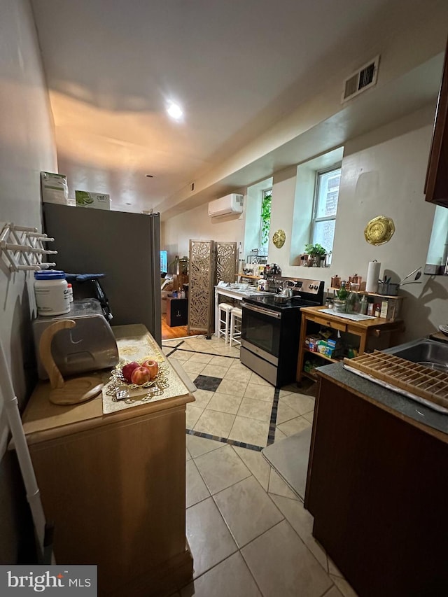 kitchen featuring stainless steel appliances, a wall unit AC, and light tile patterned floors