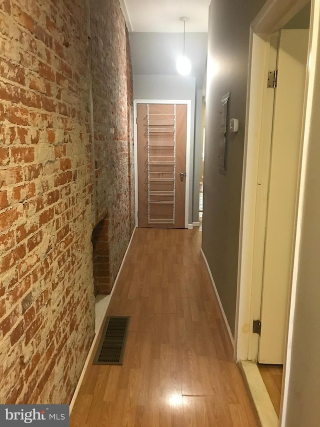 hallway featuring brick wall and hardwood / wood-style flooring