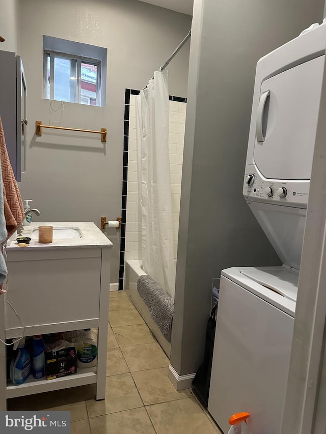 washroom with stacked washer and dryer, light tile patterned floors, and sink