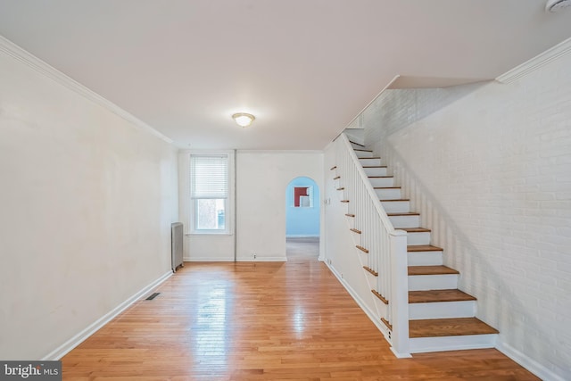 stairway featuring radiator, hardwood / wood-style floors, and crown molding