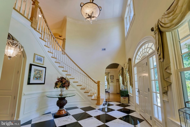 entryway featuring a high ceiling, ornamental molding, and an inviting chandelier