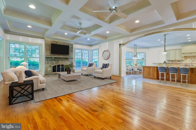 living room featuring coffered ceiling, plenty of natural light, beam ceiling, and light hardwood / wood-style flooring