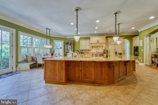 kitchen featuring pendant lighting, crown molding, tasteful backsplash, and a spacious island