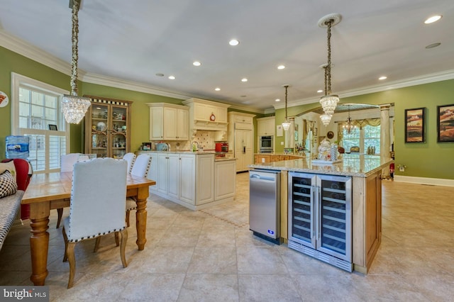 kitchen with beverage cooler, a chandelier, hanging light fixtures, cream cabinets, and a center island with sink