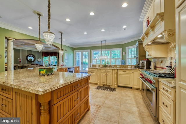 kitchen with range with two ovens, hanging light fixtures, light stone counters, crown molding, and a spacious island