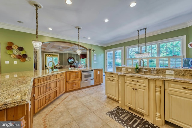 kitchen with light stone counters, stainless steel oven, and decorative light fixtures