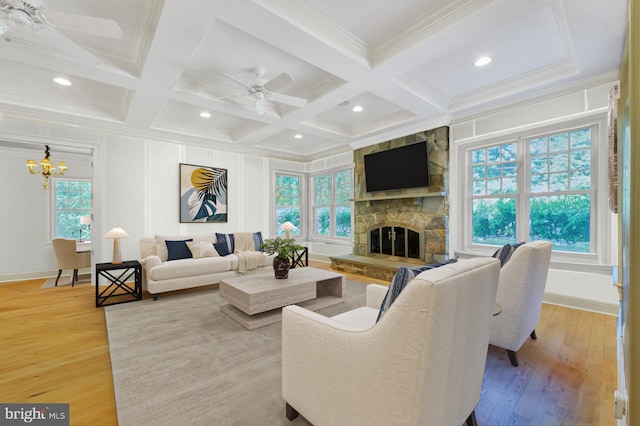 living room with ceiling fan with notable chandelier, a fireplace, hardwood / wood-style floors, coffered ceiling, and beam ceiling