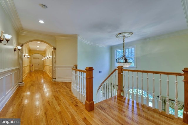 hallway with ornamental molding, a chandelier, and light hardwood / wood-style flooring