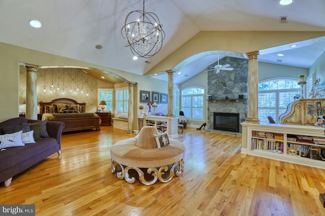 living room featuring a stone fireplace, light hardwood / wood-style flooring, and ornate columns