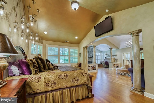 bedroom with high vaulted ceiling, hardwood / wood-style flooring, and decorative columns