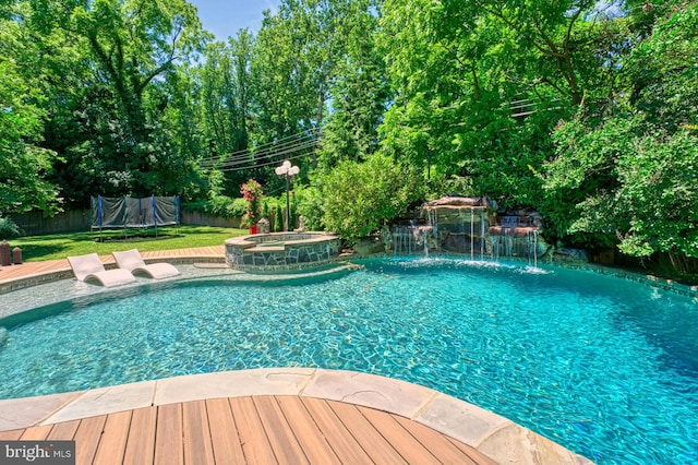 view of pool with an in ground hot tub, pool water feature, and a trampoline