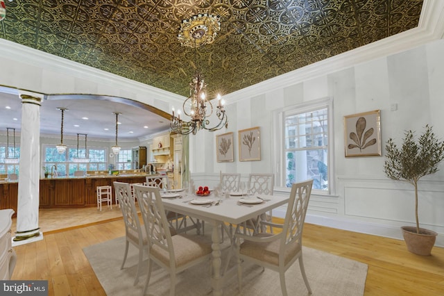 dining area with decorative columns, crown molding, plenty of natural light, and light wood-type flooring