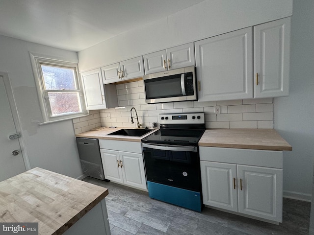 kitchen featuring appliances with stainless steel finishes, backsplash, sink, and white cabinetry