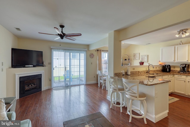 kitchen featuring white cabinetry, dark wood-type flooring, kitchen peninsula, ceiling fan, and sink