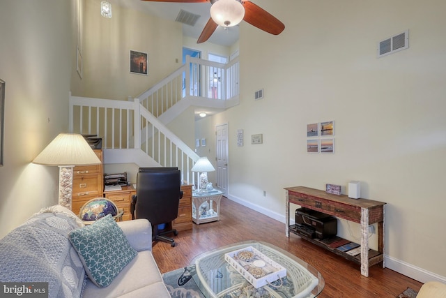 living room with a high ceiling, ceiling fan, and hardwood / wood-style flooring