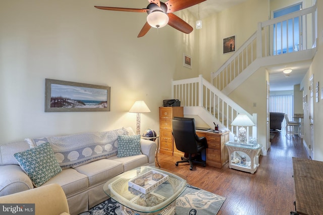 living room featuring a high ceiling, ceiling fan, and dark hardwood / wood-style flooring