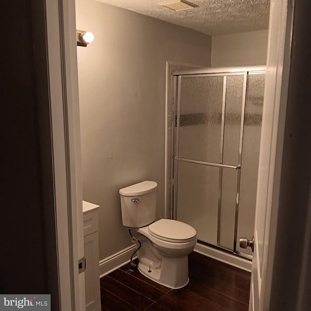 bathroom featuring wood-type flooring, a shower with shower door, vanity, and toilet