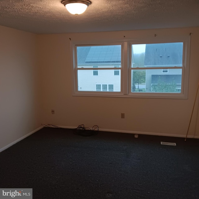 unfurnished room with a textured ceiling and carpet