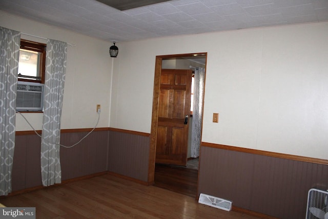 empty room with wooden walls, hardwood / wood-style floors, and crown molding