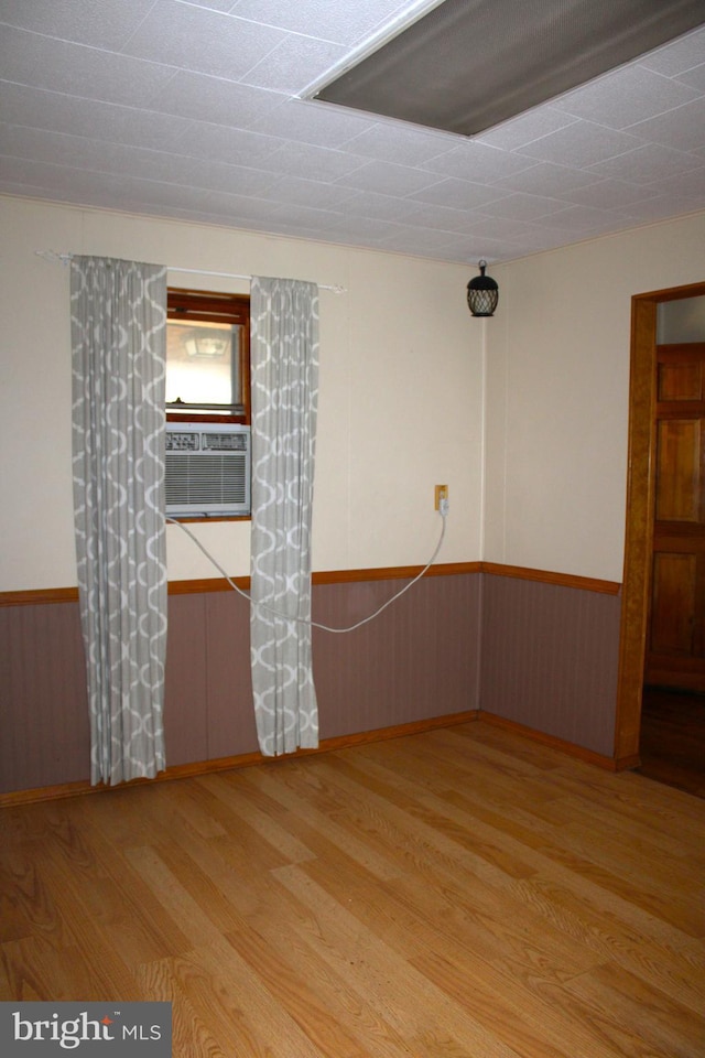 unfurnished room featuring cooling unit and light hardwood / wood-style floors