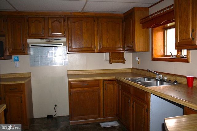 kitchen with backsplash, a paneled ceiling, and sink