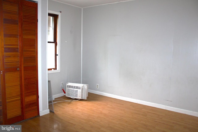 unfurnished bedroom featuring a closet, a wall unit AC, and hardwood / wood-style flooring