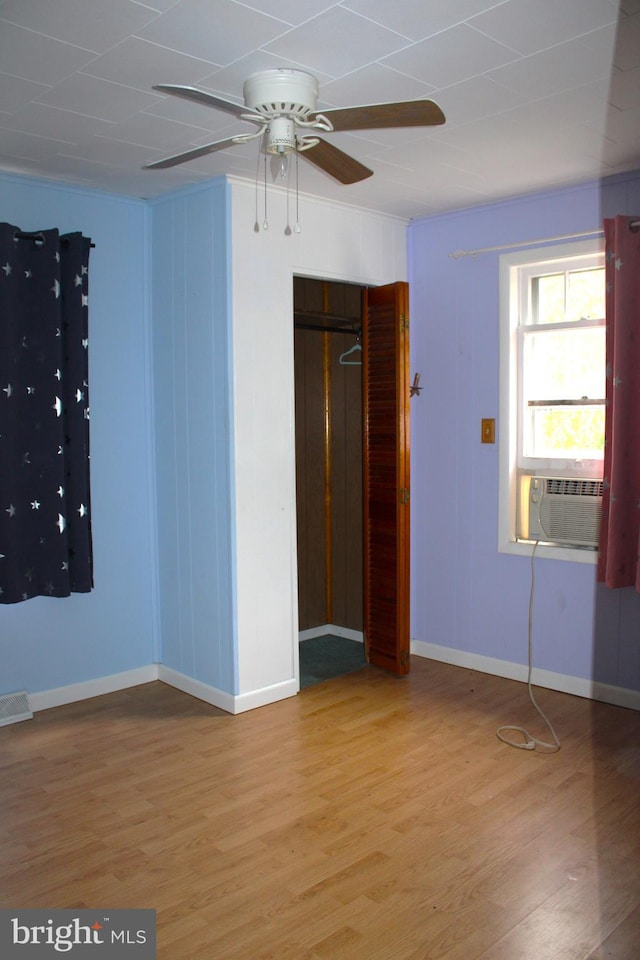 unfurnished bedroom featuring cooling unit, ceiling fan, a closet, and hardwood / wood-style flooring