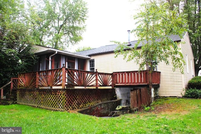 back of property featuring a wooden deck and a yard