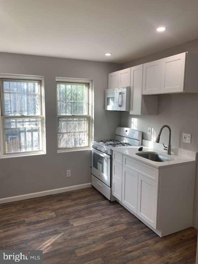 kitchen featuring high end stove, white cabinetry, dark hardwood / wood-style floors, and sink