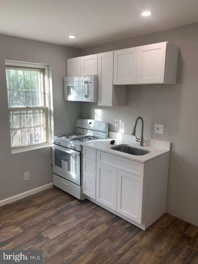 kitchen featuring white appliances, white cabinetry, sink, and dark wood-type flooring