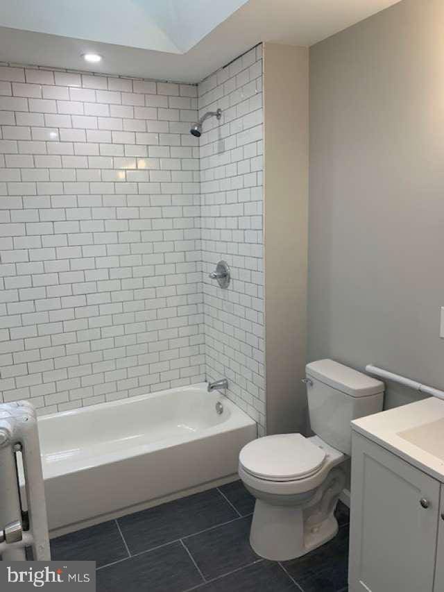 full bathroom featuring tile patterned flooring, vanity, toilet, and tiled shower / bath