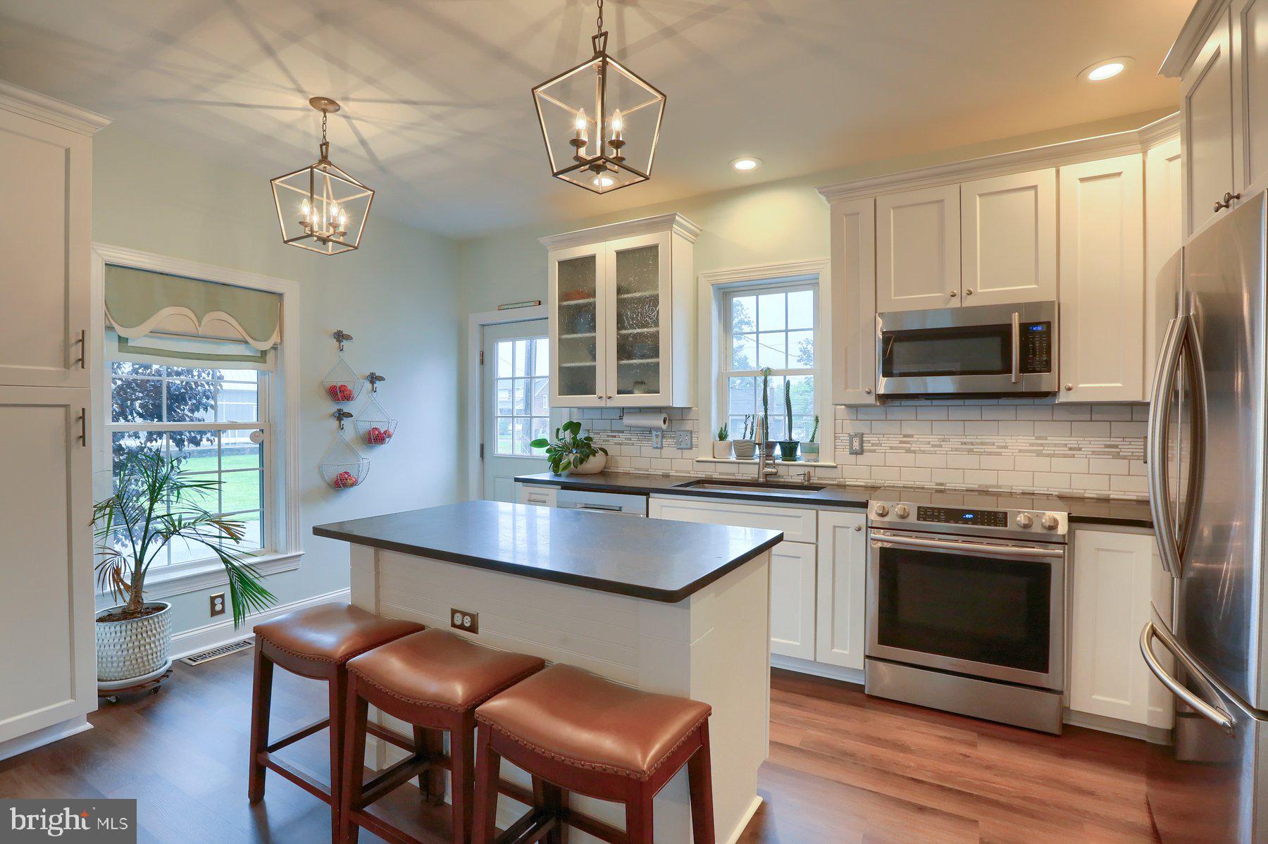 kitchen with stainless steel appliances, a chandelier, hanging light fixtures, and white cabinets