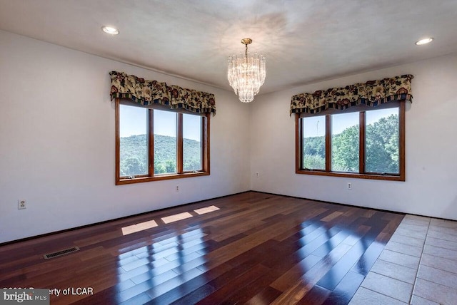 unfurnished room with an inviting chandelier and dark wood-type flooring