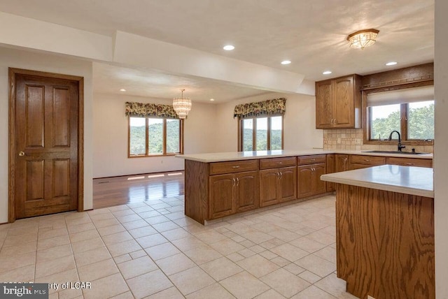 kitchen with a healthy amount of sunlight, kitchen peninsula, sink, and decorative light fixtures