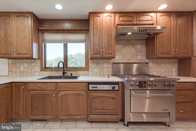 kitchen featuring light tile patterned flooring, sink, exhaust hood, high end stove, and paneled dishwasher